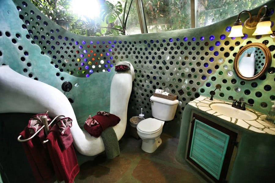 Bathroom with a curved white tub, mosaic sink, and bottle wall