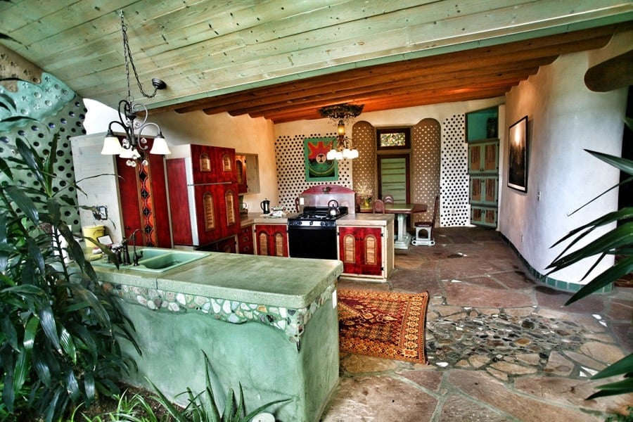 Kitchen with a concrete island, red cabinets, and a stone floor