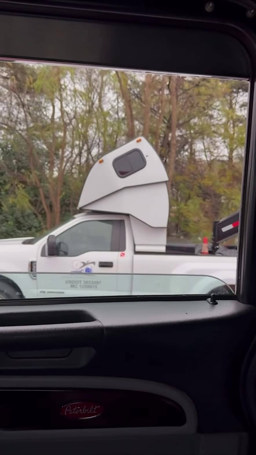 Driver door of the white hot-shot pickup showing commercial markings and the sleeper above the cab — still from the Pless Trucking reel