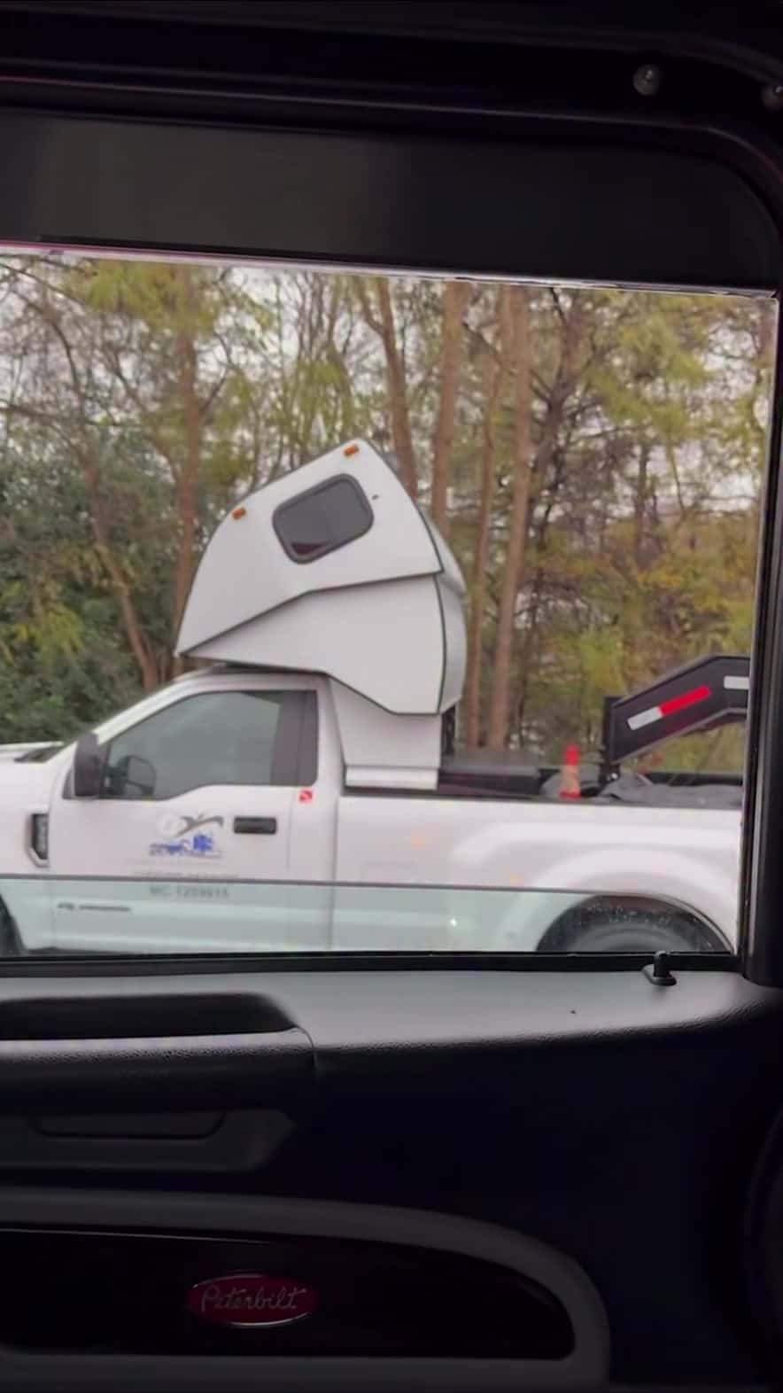 Passing shot of the white pickup and cab-over sleeper from the Peterbilt window — still from the Pless Trucking reel