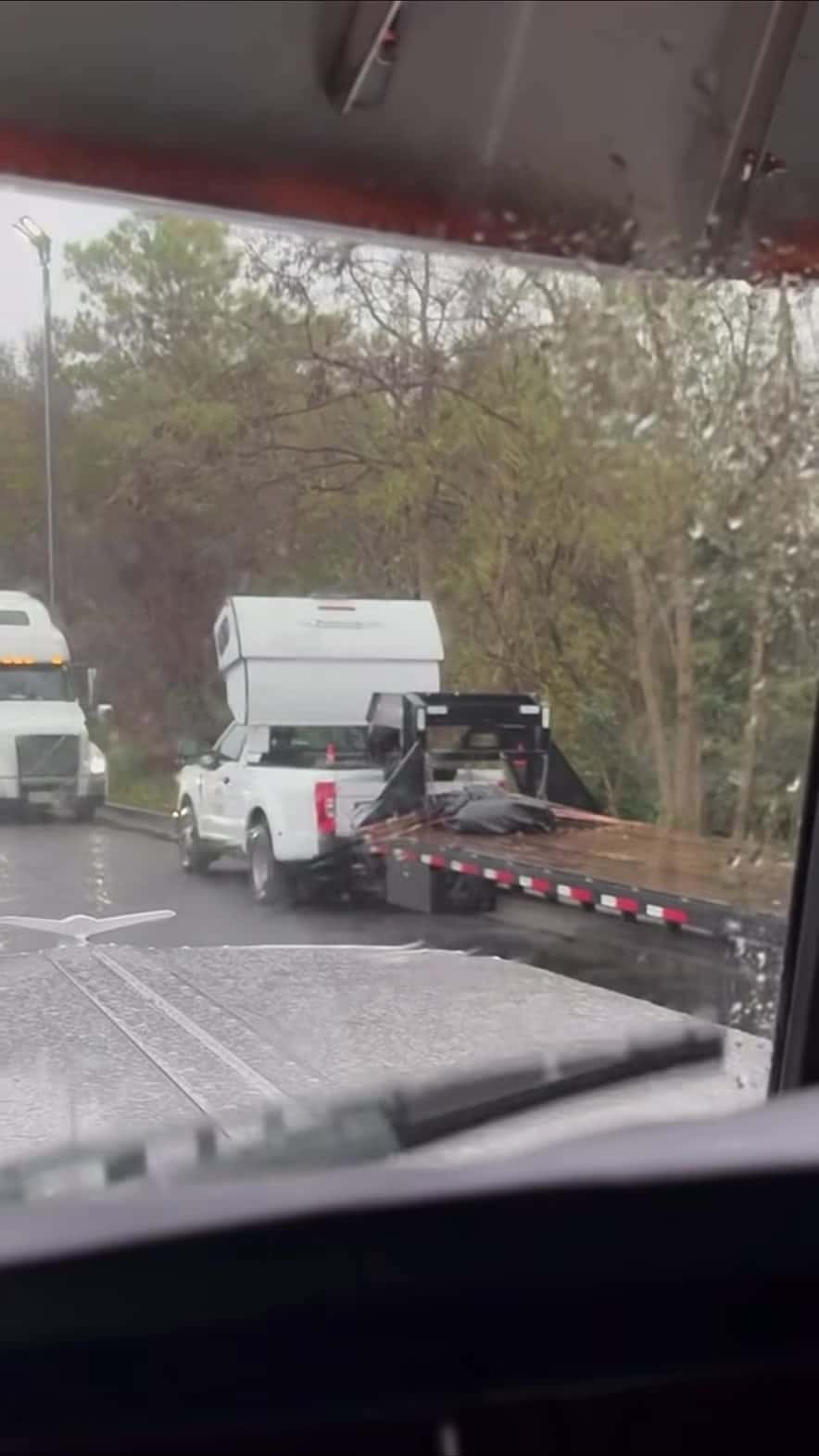 Front three-quarter of the hot-shot pickup and sleeper in the rain, gooseneck trailer attached — still from the Pless Trucking reel