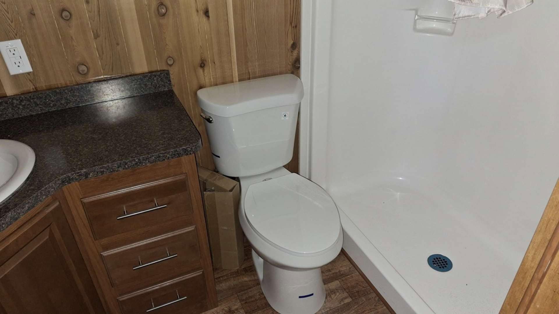 Bathroom with a wood vanity, porcelain toilet, and one-piece fiberglass shower