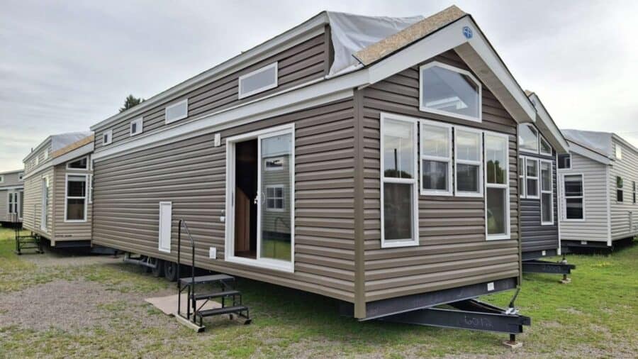 Brown Quailridge park model with white trim and a loft on a dealer lot