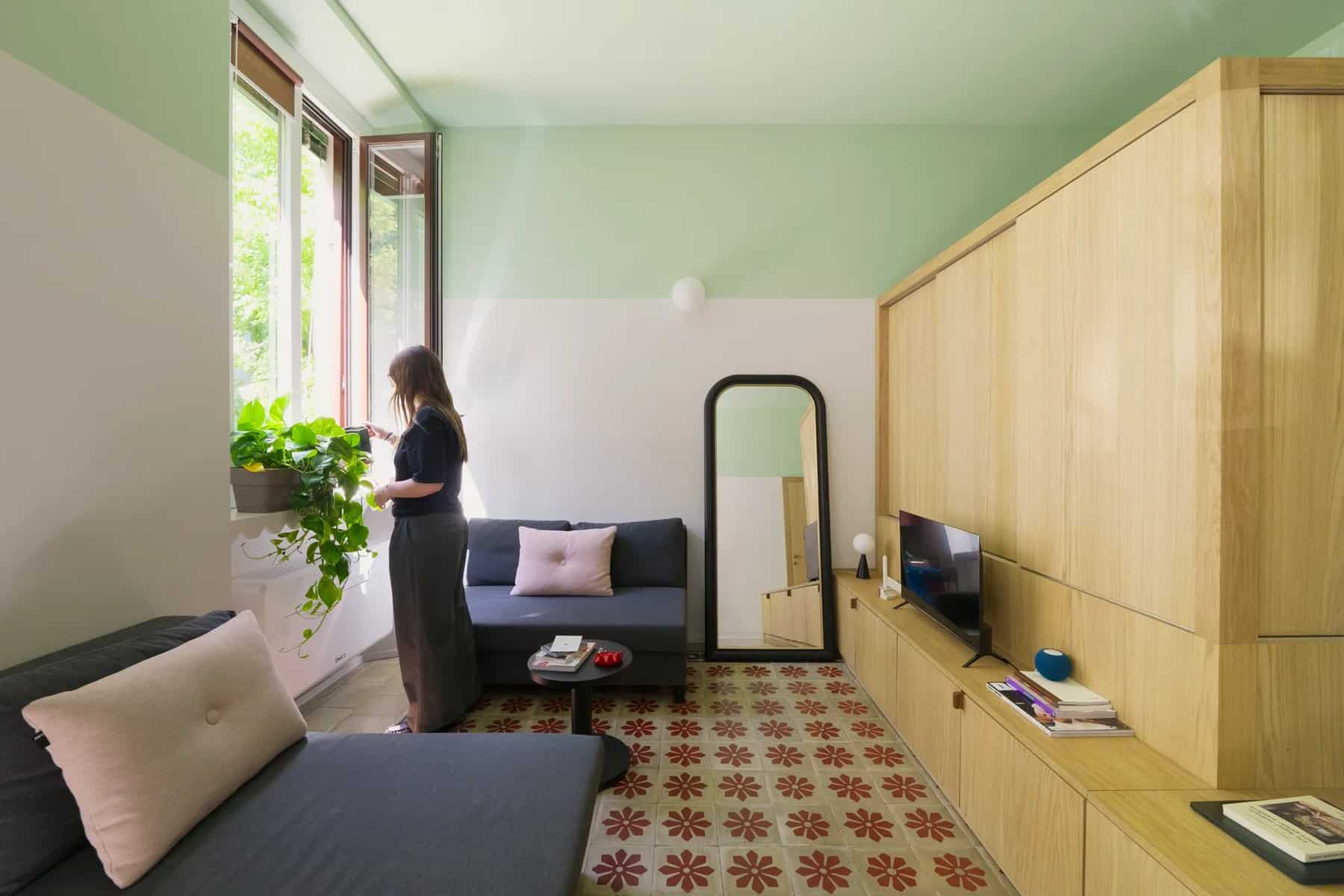 Living room with pale green upper walls, white lower walls, a gray sofa, and original patterned floor tiles