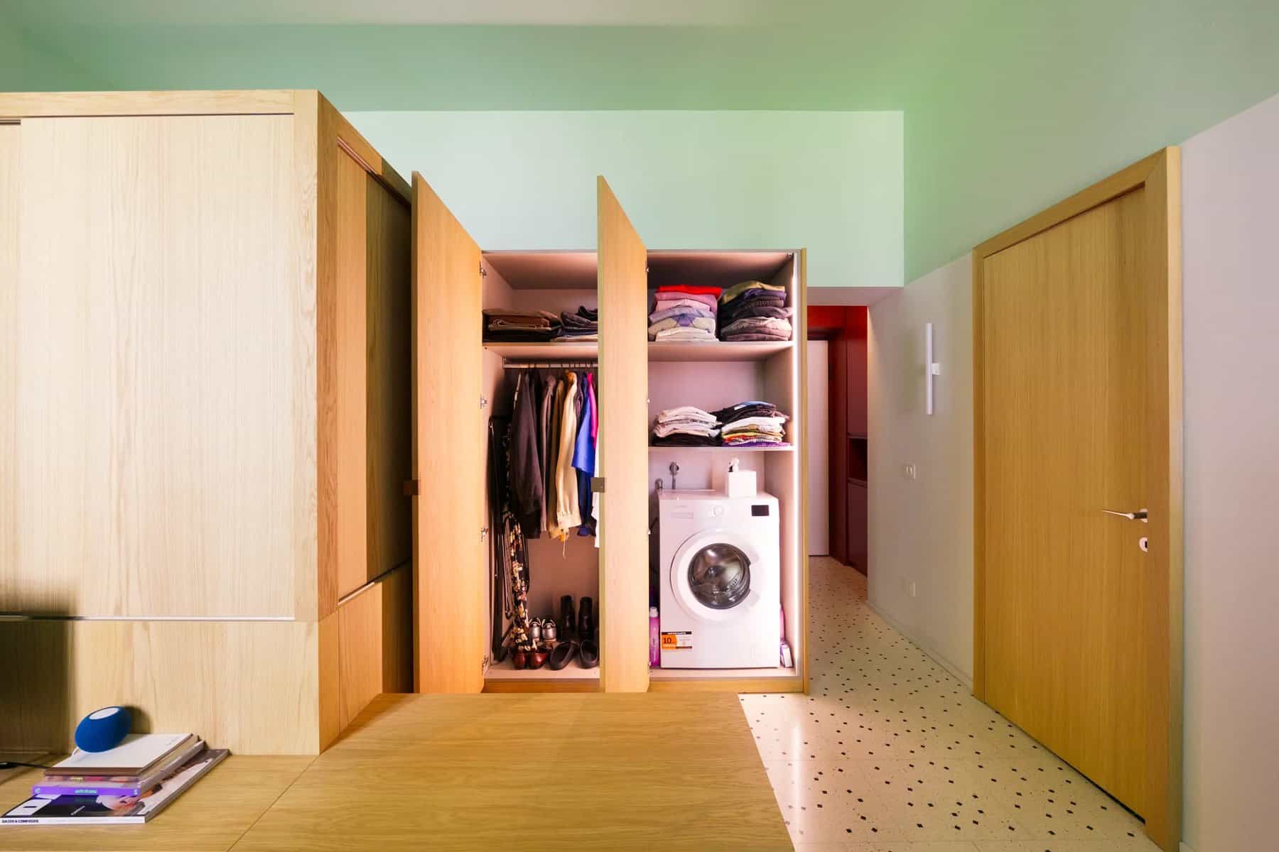 Oak cabinetry opened to show a wardrobe and a washing machine