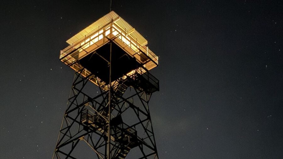 Lit 14-by-14 lookout cab on an 80-foot lattice tower under stars, Red Oak Fire Lookout, Monongahela National Forest