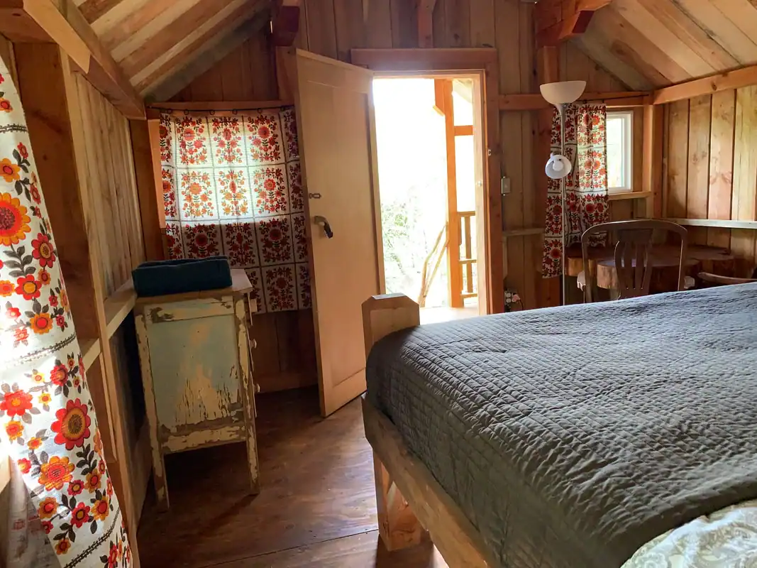 Interior of King Wood Cabin: king bed with white linens, door open to the private balcony