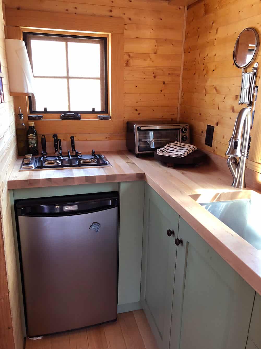 Corner of the kitchen with a two-burner propane cooktop, toaster oven, under-counter fridge, and butcher block counters