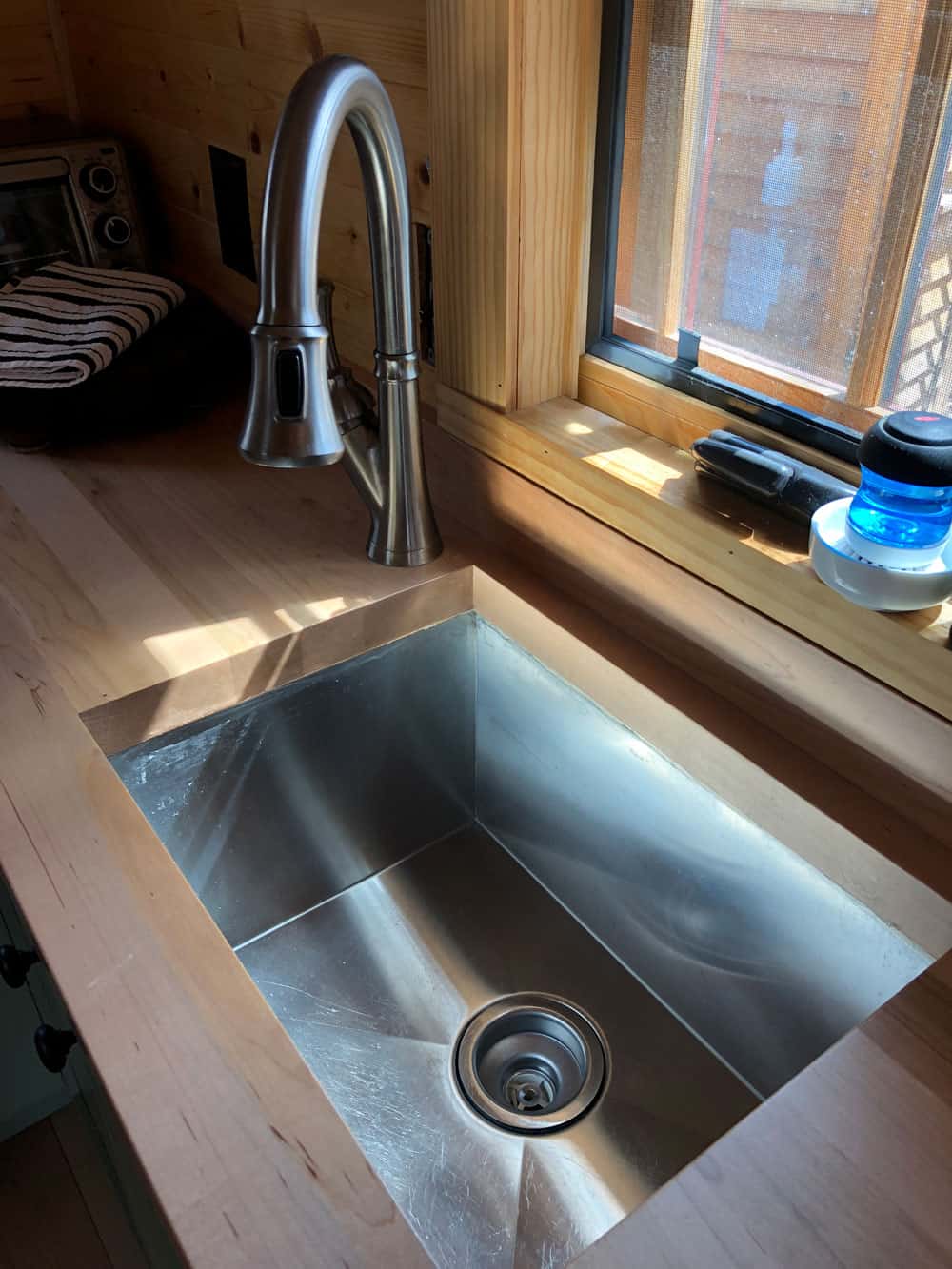 Deep stainless steel sink with a pull-down faucet set into a butcher block counter
