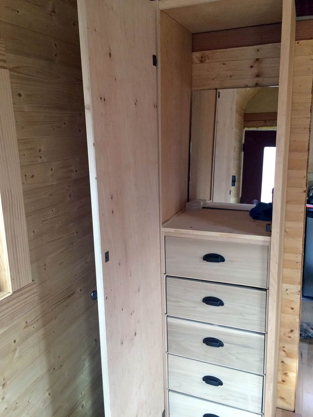 Tall built-in pine wardrobe with five drawers and a mirror