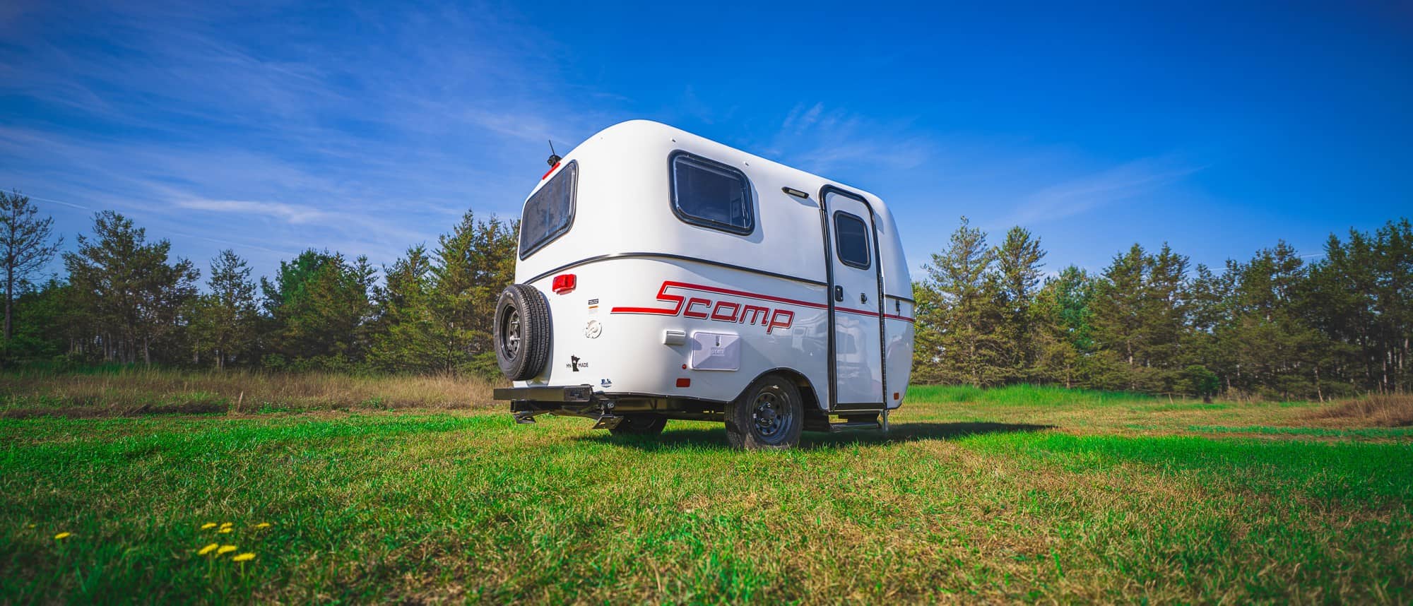 Rear three-quarter of a white Scamp with a red stripe