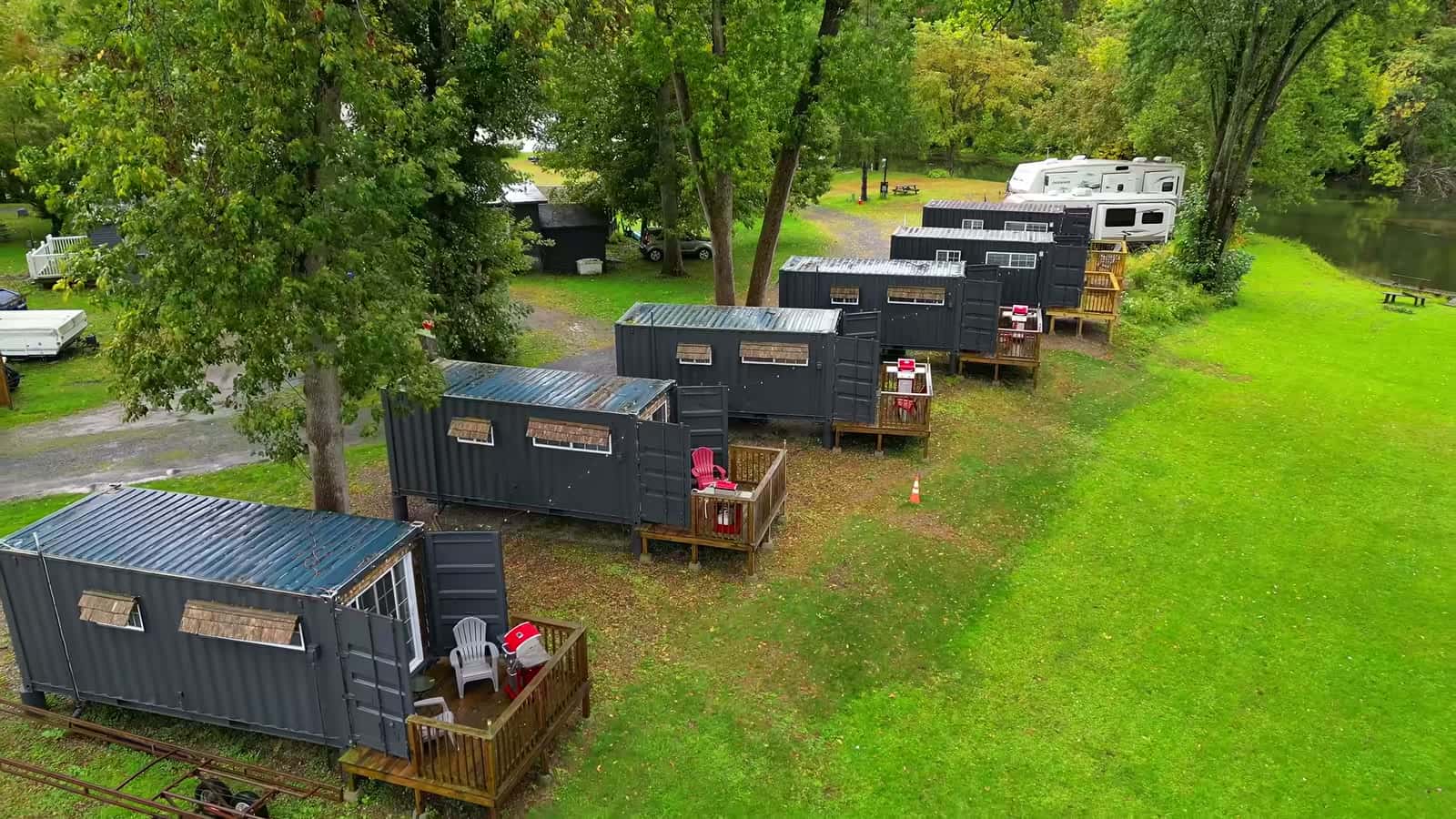Aerial view of a row of dark gray shipping container cabins along a grassy lane at Schuyler Yacht Basin