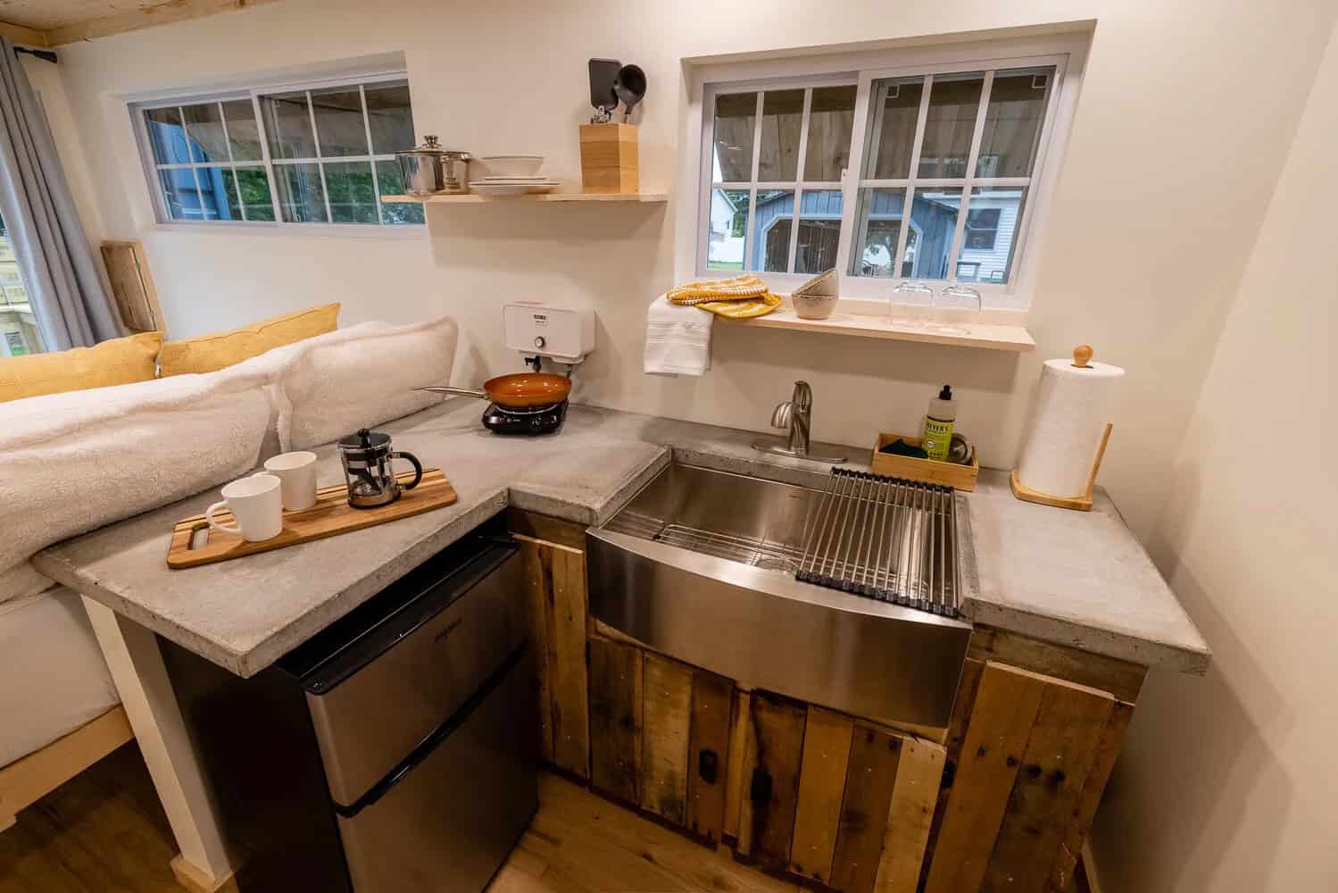 Container cabin kitchenette with concrete counter, farmhouse sink, and wood cabinets