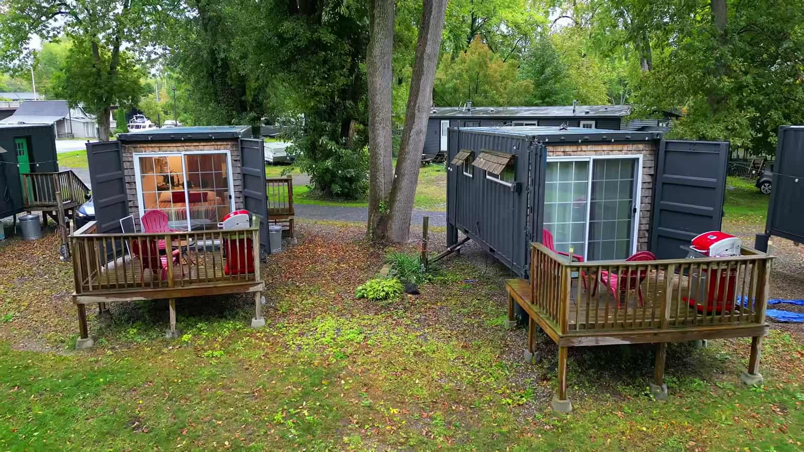 Two container cabins with private decks, red Adirondack chairs, and glass doors