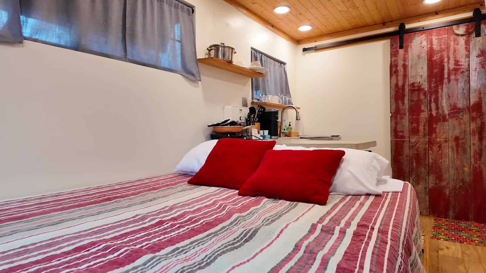Striped queen bed in front of sliding glass doors opening to a deck