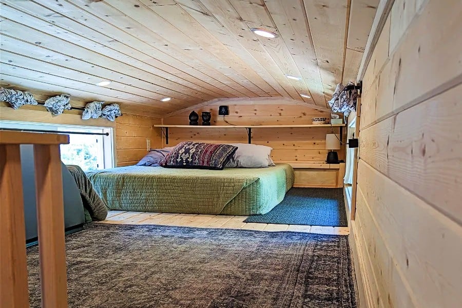 Compact tiny house bedroom with wooden interior and comfortable bed.