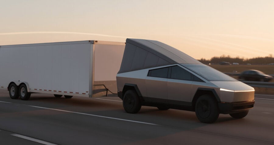 Electric vehicle towing a tiny house trailer on highway at sunset.