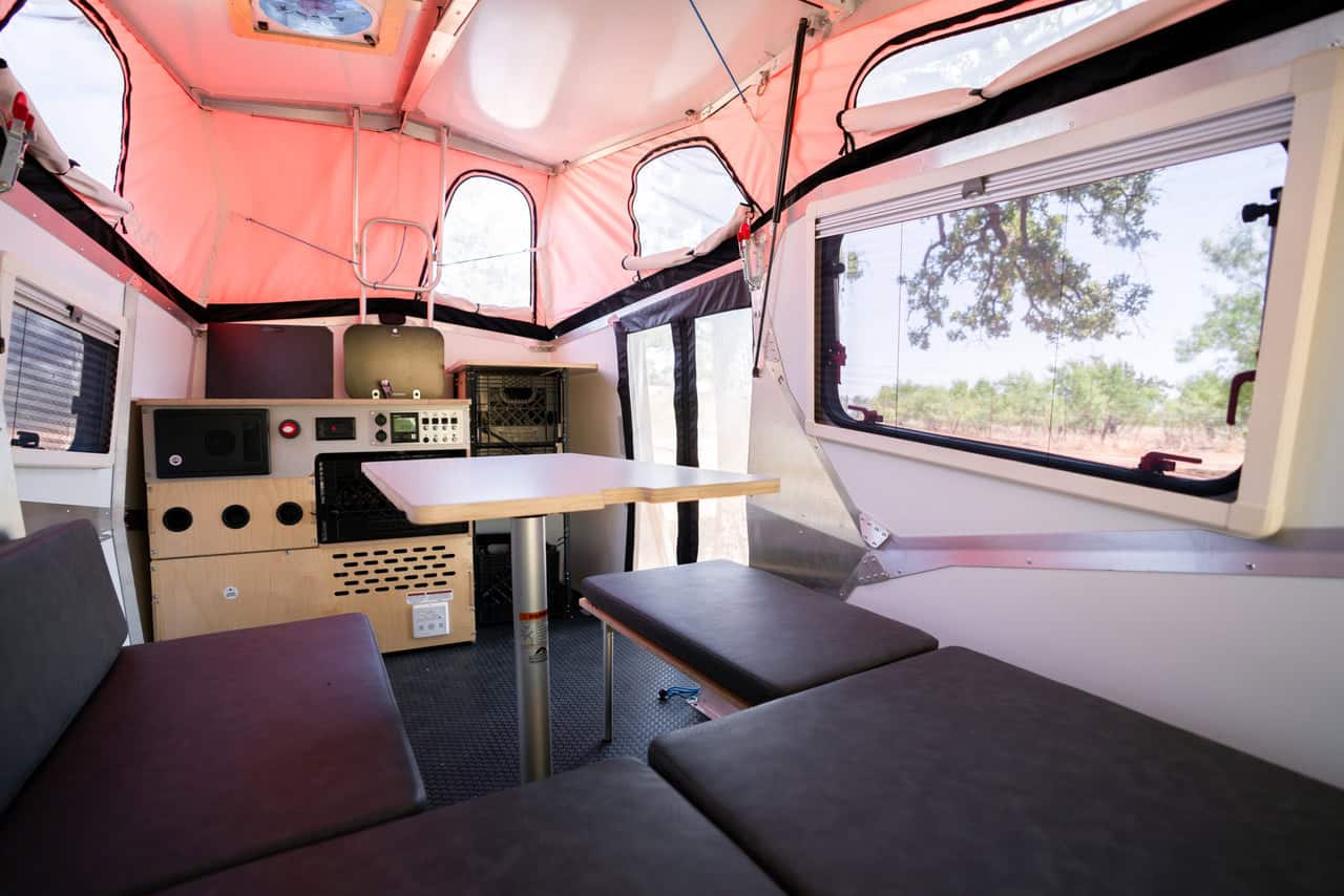 Cozy tiny house interior with foldable seating and large windows for natural light.