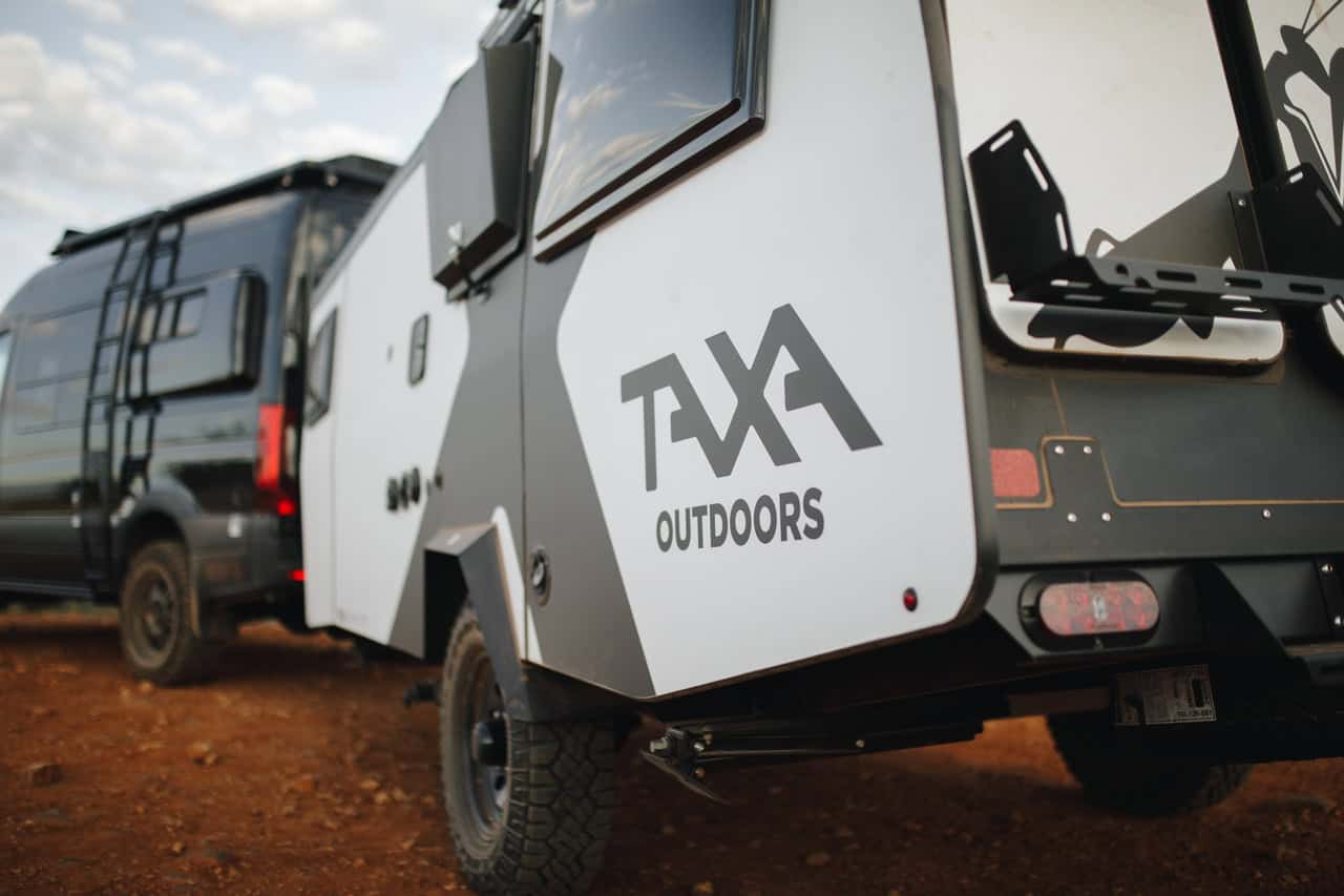 Compact off-grid tiny house on wheels with outdoor storage and rugged tires.