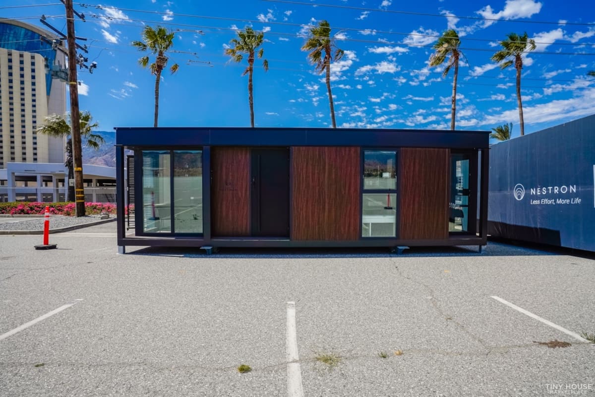 Contemporary tiny house with expansive glass windows and wooden accents in an outdoor setting.