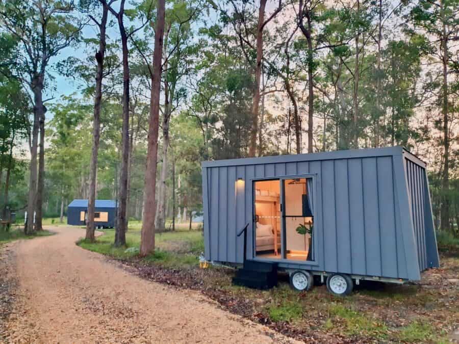 Charming tiny house with large windows nestled among tall trees in a peaceful forest. Perfect for mi.