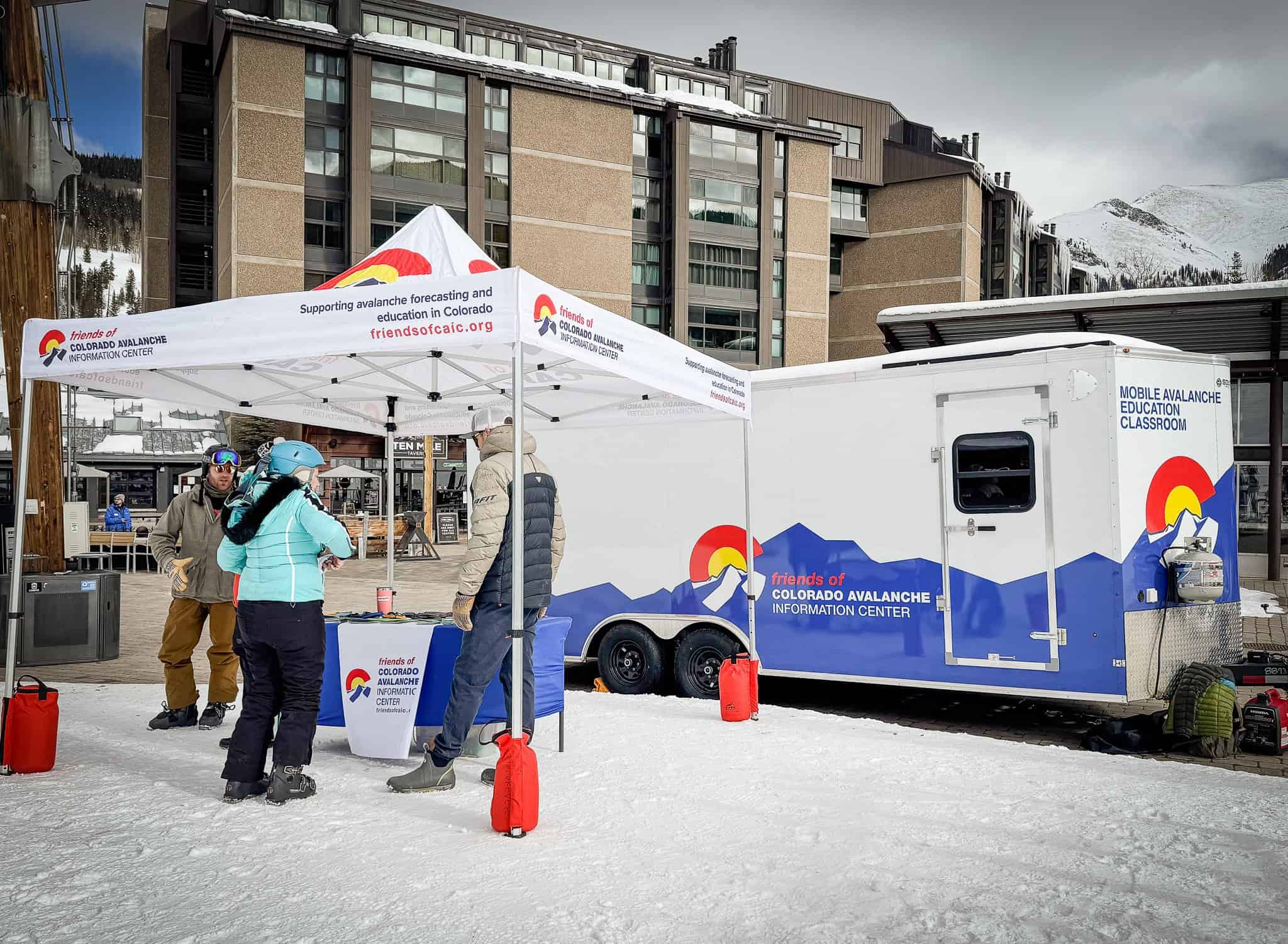 Mobile Avalanche Info Center at outdoor event in snowy urban setting.