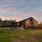Contemporary tiny house with black siding and large windows in a scenic outdoor setting.