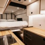 Compact tiny house interior with sleeping area and kitchen workspace.