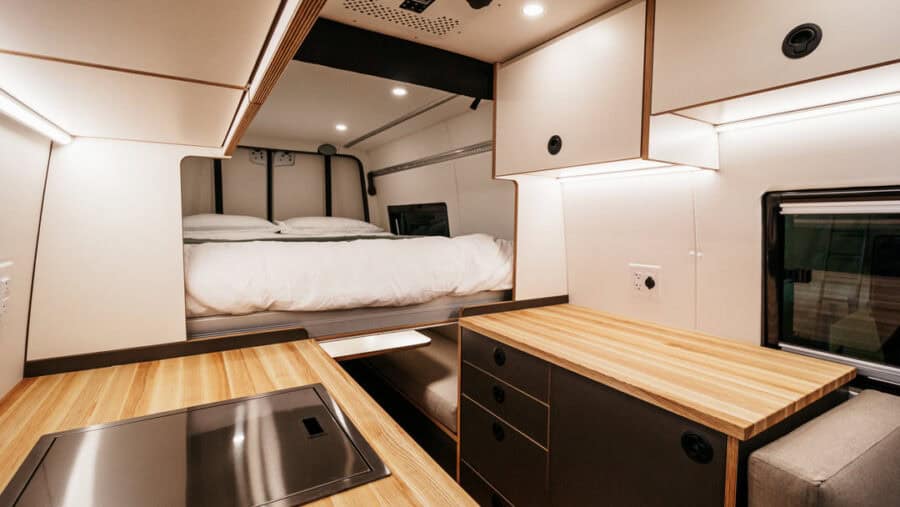 Compact tiny house interior with sleeping area and kitchen workspace.