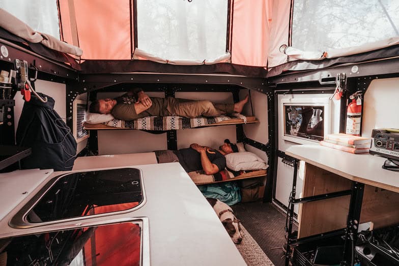 Cozy tiny house interior with multi-level sleeping bunks and compact kitchen space.