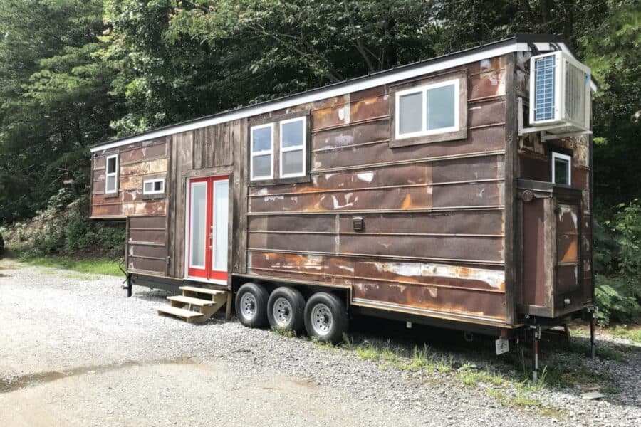Rustic tiny house on wheels with weathered wood siding and modern windows.