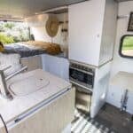 Efficient tiny house interior featuring a small kitchen, bed, and workspace for comfortable living i.