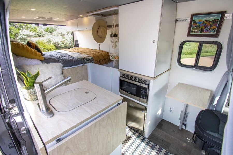 Efficient tiny house interior featuring a small kitchen, bed, and workspace for comfortable living i.