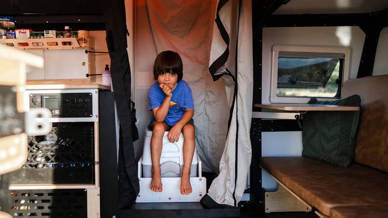 Child sitting inside a tiny house with compact living space.