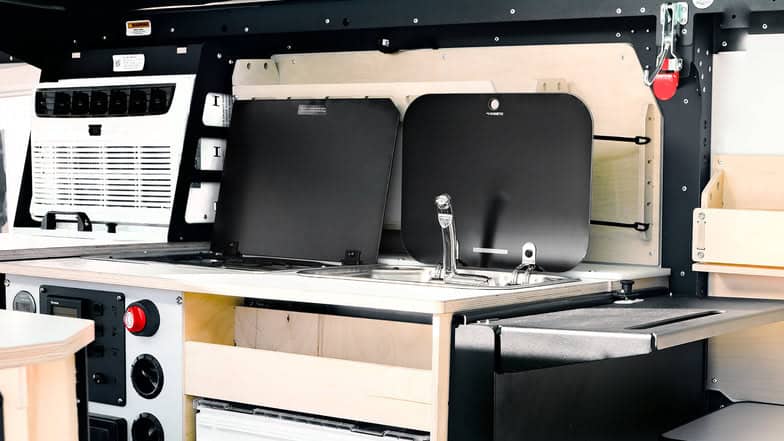 Compact tiny house kitchen with sink, stove, and storage solutions.