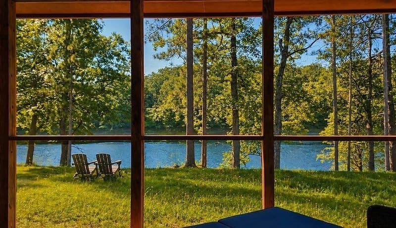 Shoreline cabin exterior glowing warm at twilight in a wildflower meadow at Canoe Bay Village Lot 16