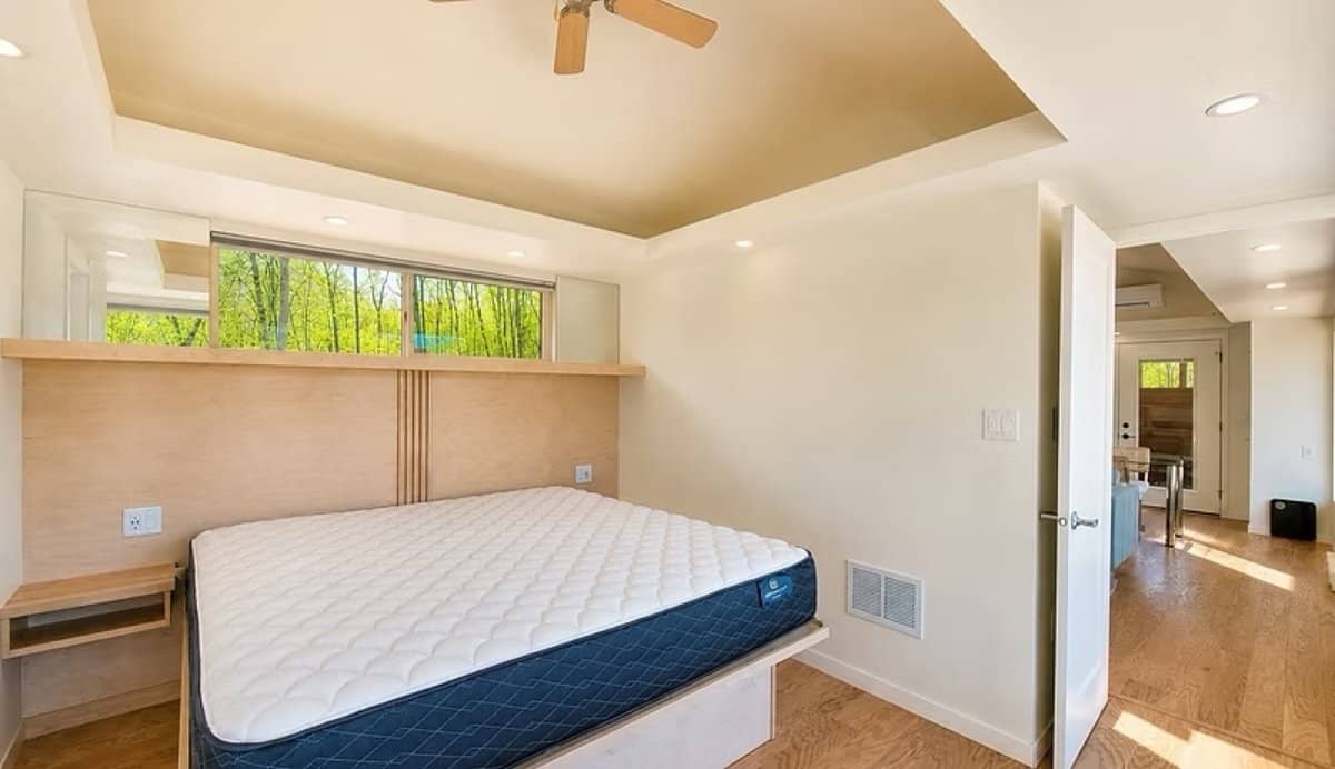 King bedroom with a tray ceiling, ceiling fan, and a clerestory window above the maple headboard in the SHORELINE Glass House Lot 21