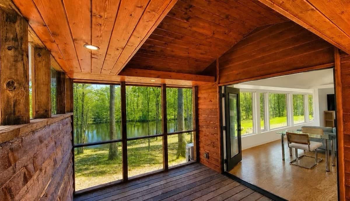 Cedar-lined screened porch with direct Lost Lake views and an open glass door into the living room of the SHORELINE Glass House Lot 21