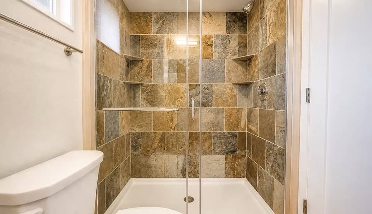 Large walk-in shower with a glass enclosure and stone tile surround in the SHORELINE Glass House Lot 21