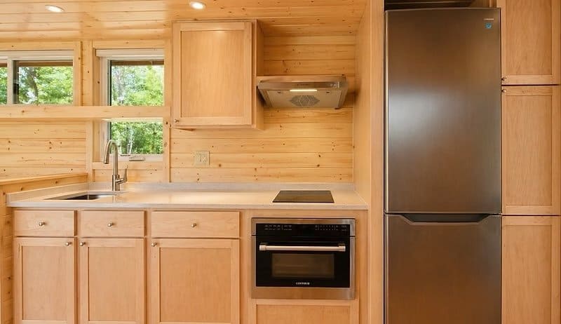 All-electric kitchen with stone counters, induction cooktop, wall oven, and a tall stainless fridge at the Shoreline Lot 16