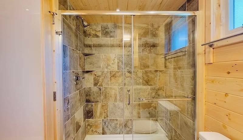 Bathroom with a stone vanity and a built-in washer/dryer against knotty-pine walls at the Shoreline Lot 16