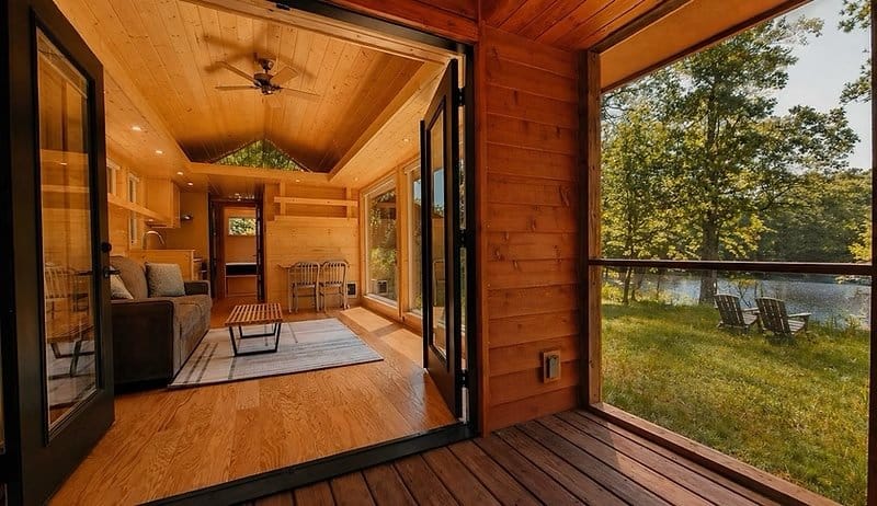 View from the screened porch through wide-open glass French doors into the open living area at the Shoreline Lot 16