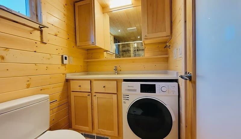 Walk-in tile shower with sliding glass doors and earth-toned stone tile against knotty-pine walls at the Shoreline Lot 16