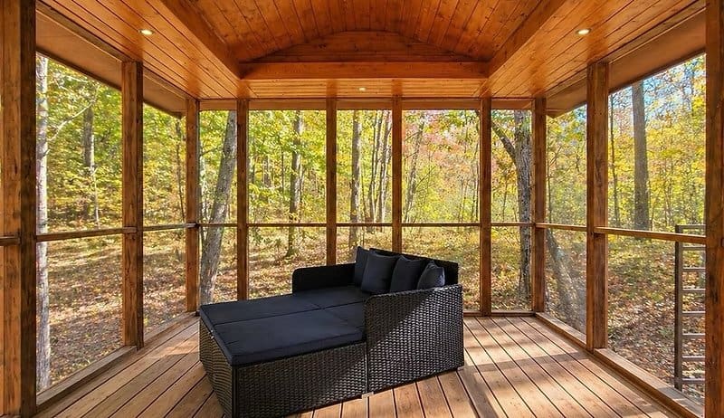 Oversized screened porch with a daybed and forest views at the Shoreline Lot 19
