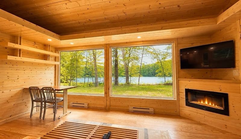 Great room with electric fireplace, wall-mounted TV, and dining table framing panoramic Lost Lake views at the Shoreline Lot 23