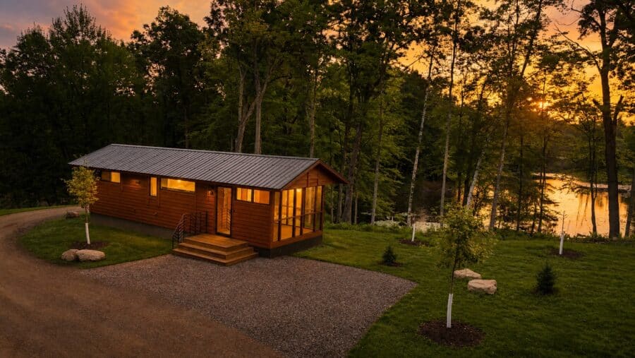 Shoreline cabin exterior with wood siding, metal roof, and screened porch at sunset on Lost Lake, Canoe Bay Village Lot 24