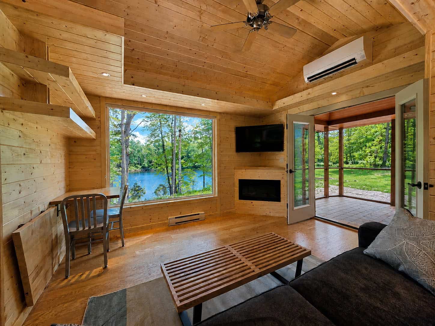 Light-filled great room with lake-view window, electric fireplace, and French doors to the screened porch at Shoreline Lot 24