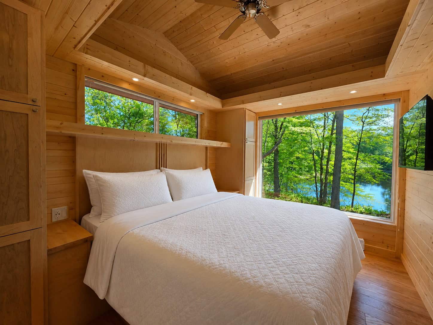 King bedroom with built-in cabinetry and a large window overlooking the forest and Lost Lake at Shoreline Lot 24