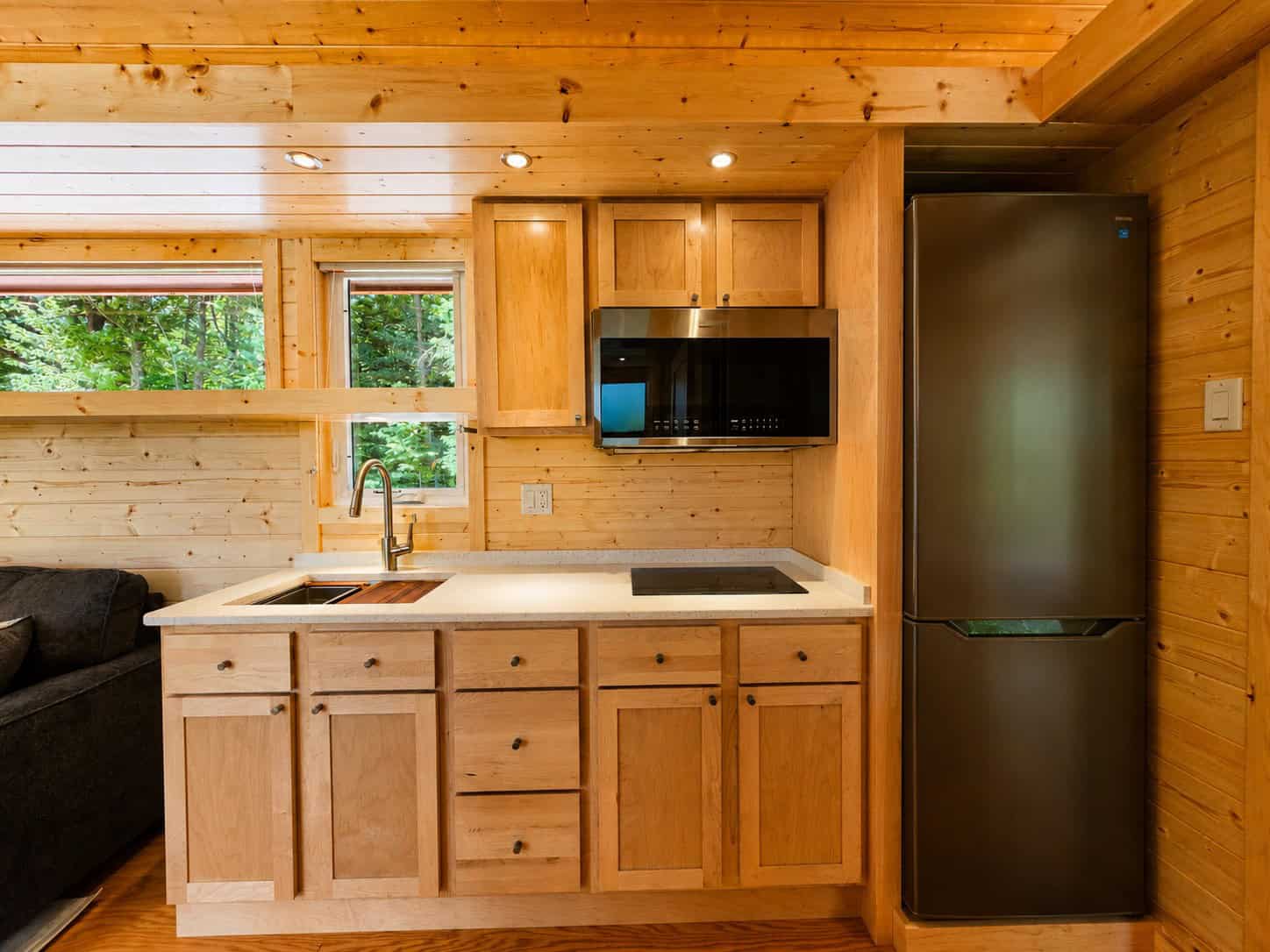 Fully equipped kitchen with wood cabinetry, cooktop, microwave, and forest views at Shoreline Lot 24