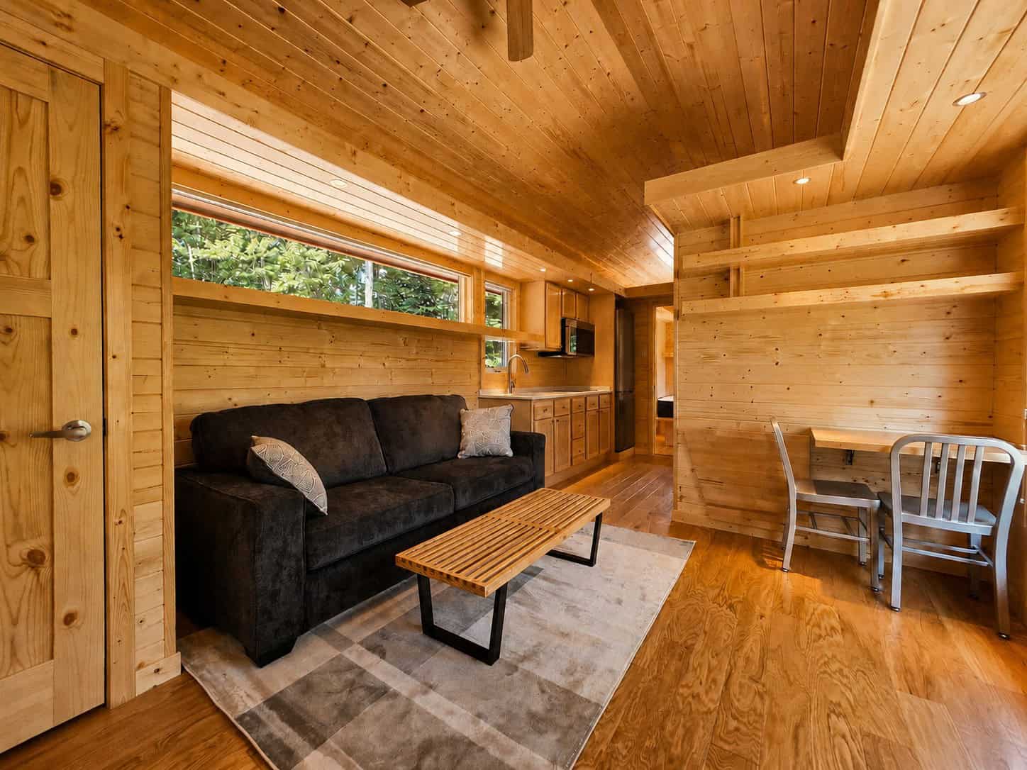 Open living area with sofa, coffee table, dining nook, and kitchen beyond at Shoreline Lot 24